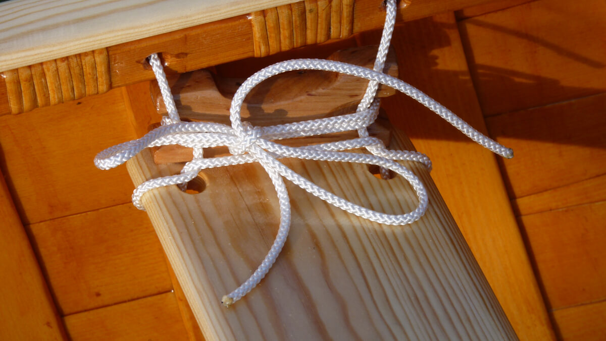 Detaik shot of an instakked suspended Seat for wooden canoe handcraftet with strings tied into the boat